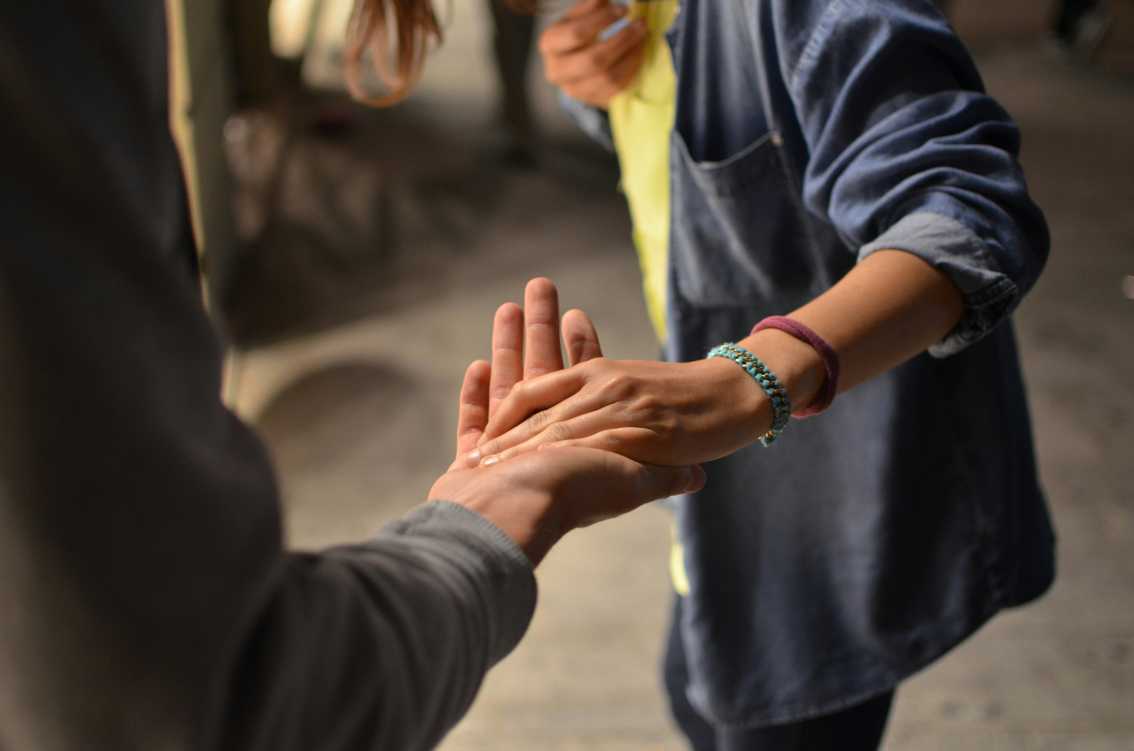 A person reaching out to hold another person's hand
