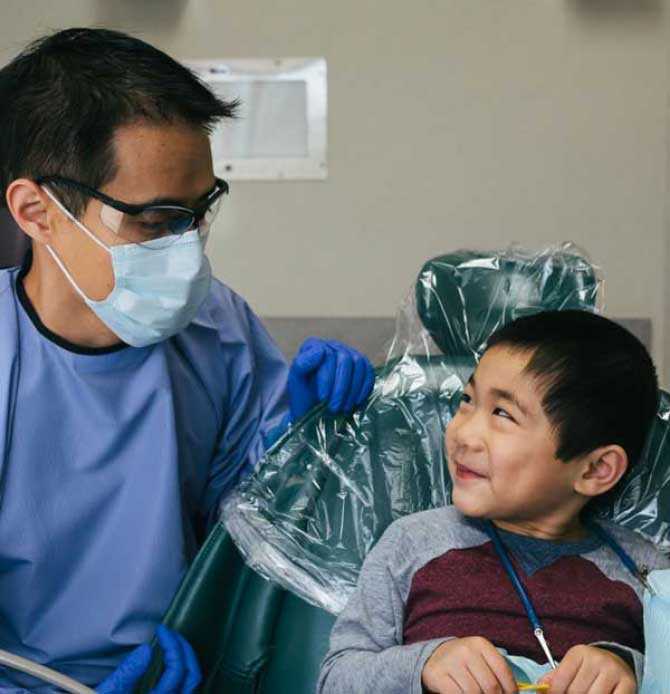 Dentist in mask looking at child patient